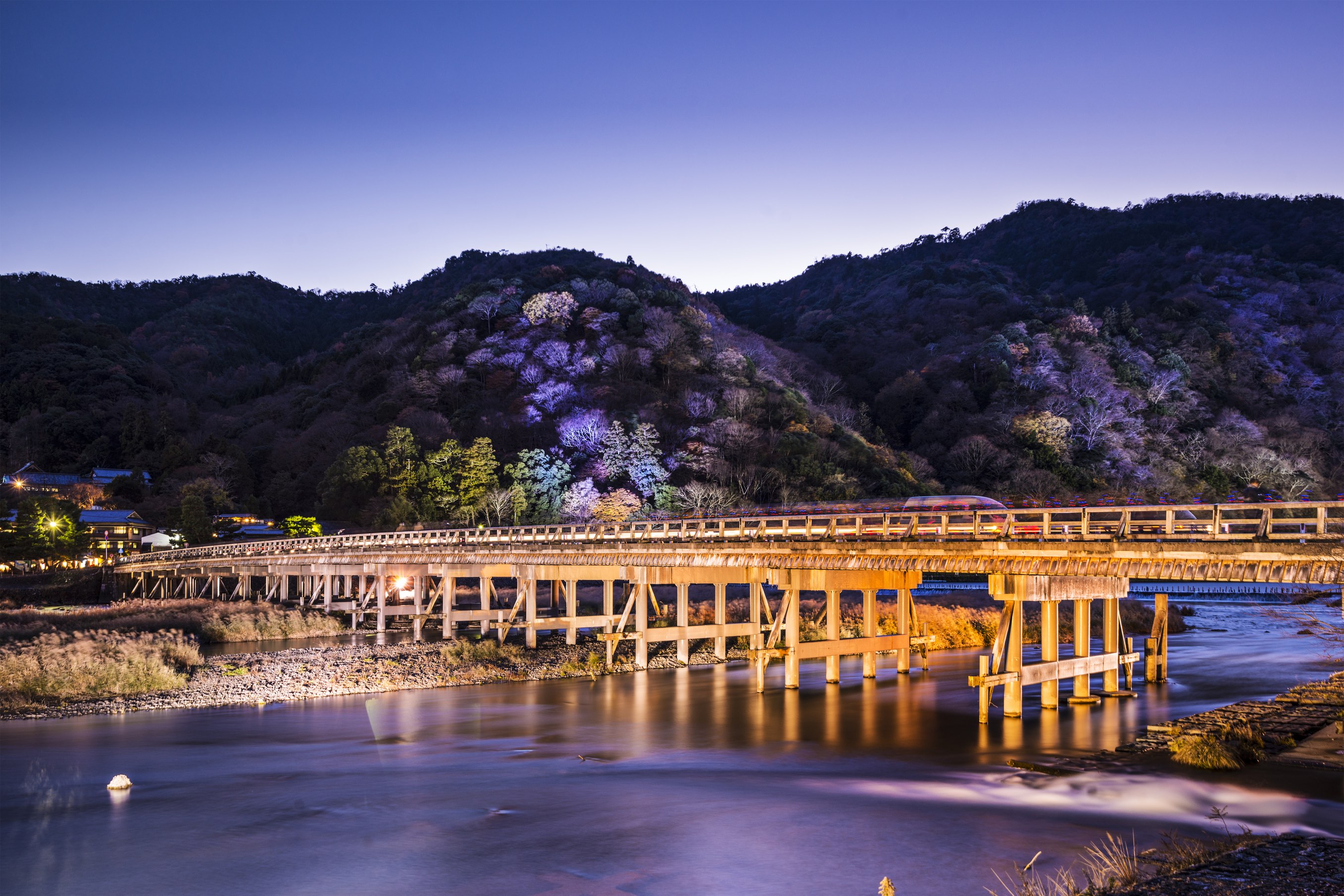 Historic Togetsukyo Bridge spanning across Katsura River in Arashiyama district with traditional architecture and mountain backdrop